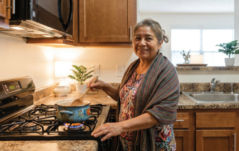 Two women and a child are in a kitchen, preparing food. One woman is wearing an apron and is reaching for a bowl of fruit. The other woman is also wearing an apron and is reaching for a bowl of fruit. The child is also reaching for a bowl of fruit. AI generated content