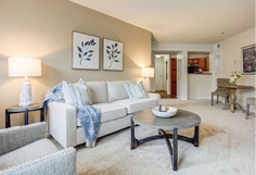 A living room with a couch, chair, and coffee table. A painting hangs above the couch. A vase is on the coffee table. AI generated content