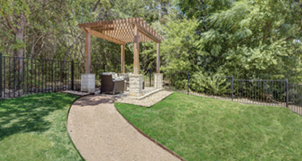 A gazebo is located in a grassy area with a bench underneath it. The gazebo is surrounded by trees and a fence. AI generated content